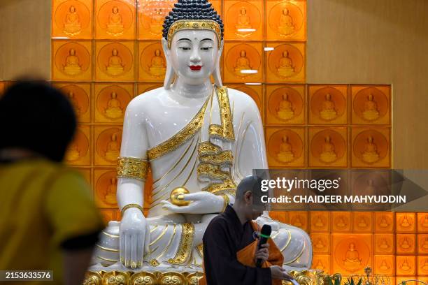 Buddhist monk speaks to devotees at Buddha Sakyamuni temple in Banda Aceh on May 23, 2024 as they mark Vesak festival which commemorates the birth,...