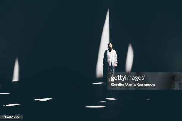 thoughtful woman standing and looking up in the light. - reincarnação imagens e fotografias de stock