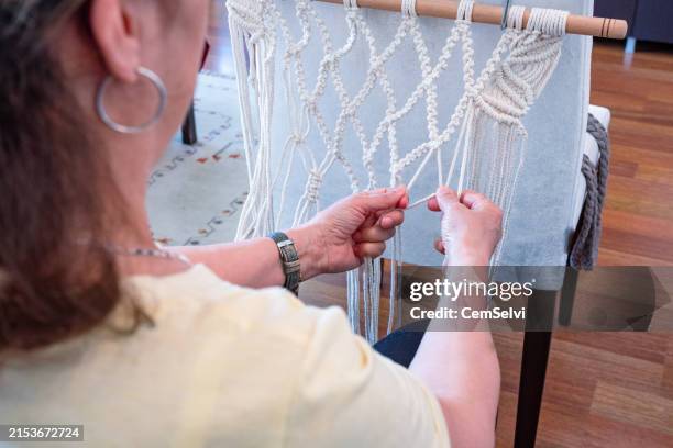 une femme de 60+ ans qui tisse du macramé, s’épanouissant dans son nouveau passe-temps et son mode de vie actif - tisser photos et images de collection