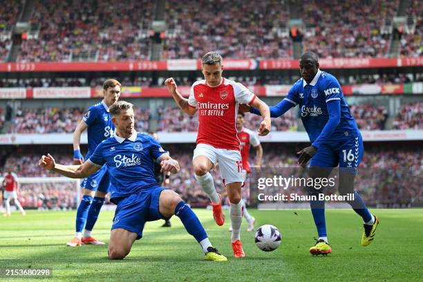 Leandro Trossard of Arsenal is challenged by James Tarkowski and Abdoulaye Doucoure of Everton during the Premier League match between Arsenal FC and...