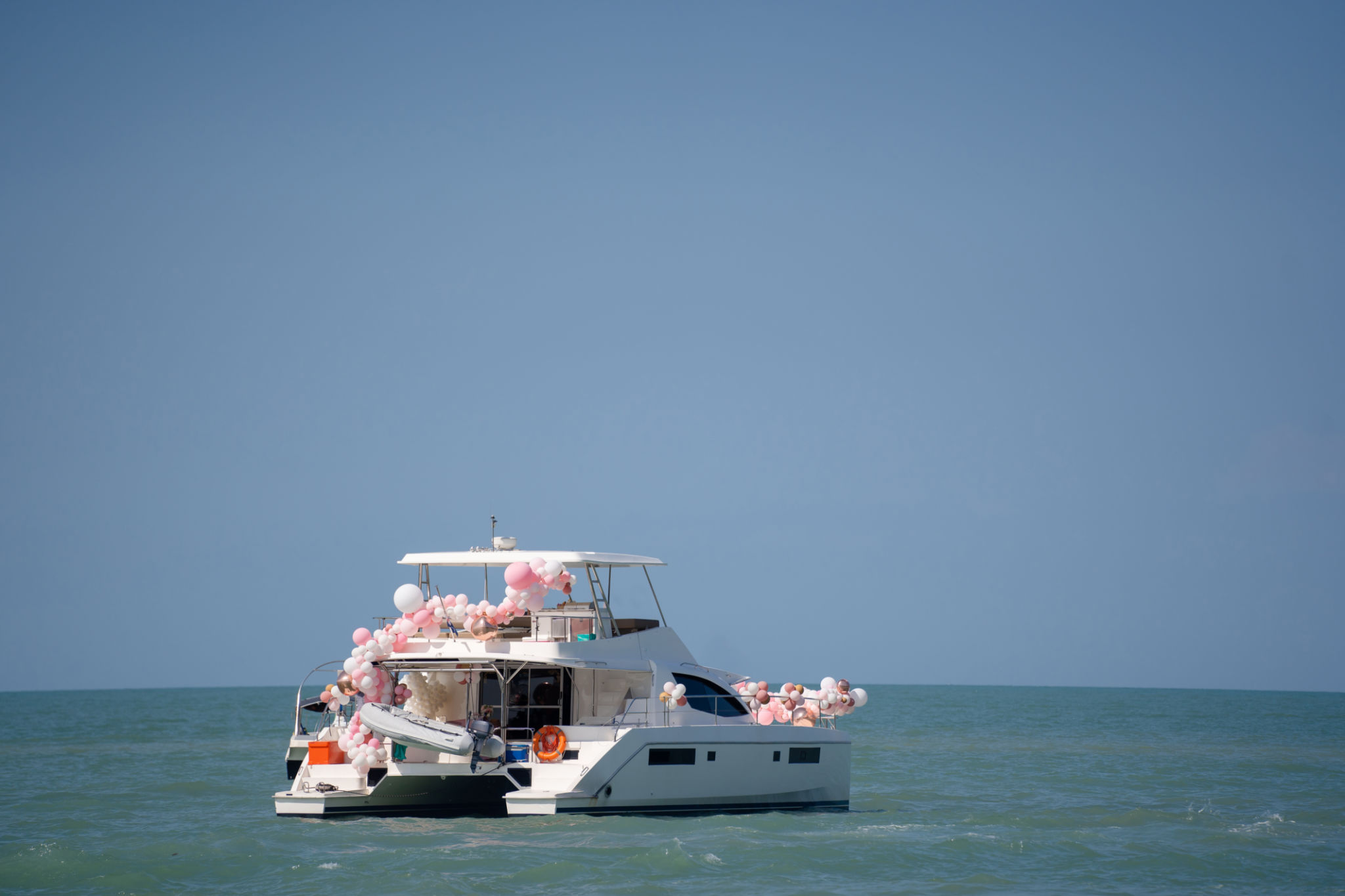 Private yacht adorned with festive balloons on the open sea Private yacht adorned with festive balloons on the open sea
