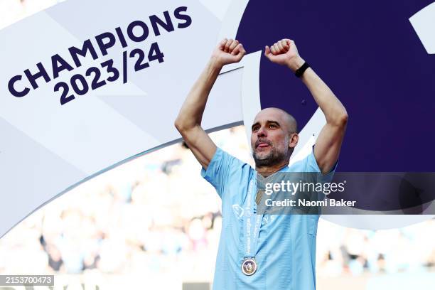 Pep Guardiola, Manager of Manchester City, celebrates with his Winners Medal as he acknowledges the fans from the Winners Podium after the Premier...