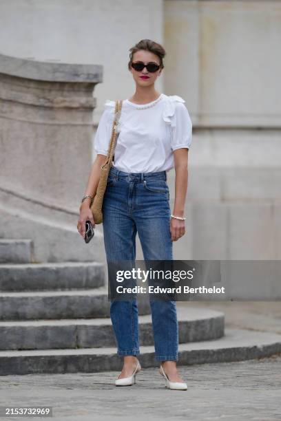 Segolene Hyppolite wears sunglasses from Jimmy Fairly, red lipstick, a white ruffled top from Simone Rochas, a large raffia bag in brown from Agnes...
