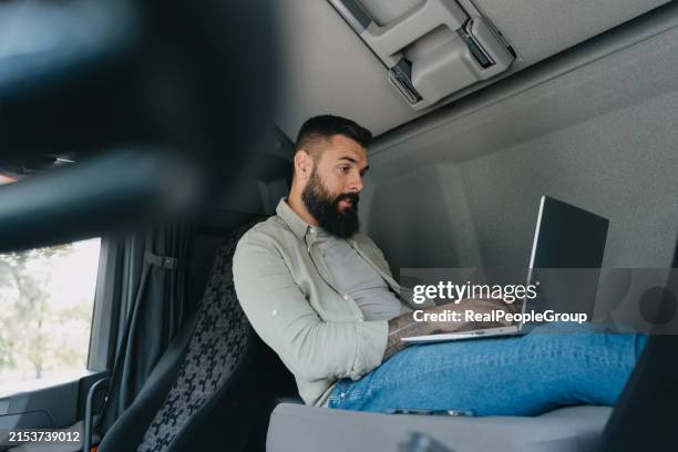 bärtiger mann mit laptop in lkw-kabine - lkw kabine stock-fotos und bilder