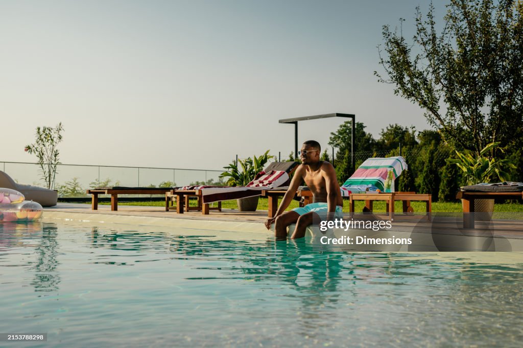 Sitting By Pool Rapper Young Man Sitting On The Side Of The Pool Smiling High-Res Stock Photo ...