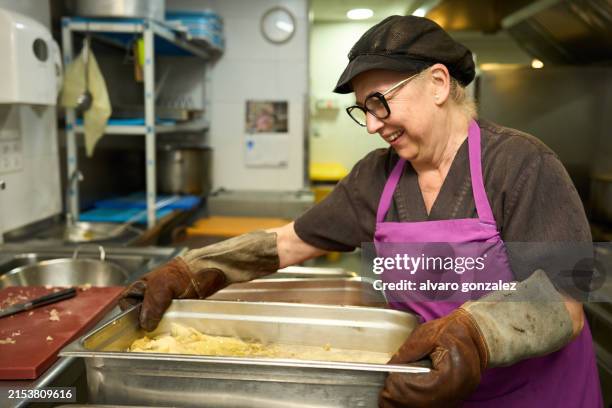 woman in apron preparing food in kitchen - avental imagens e fotografias de stock