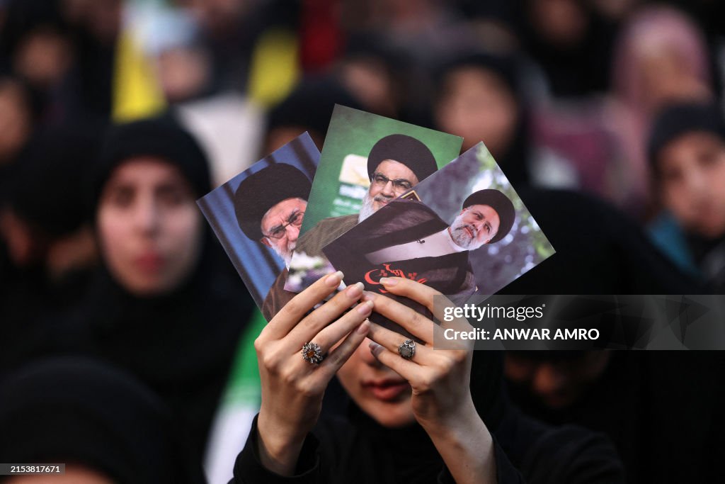 TOPSHOT - A woman holds pictures of Iran's late president Ebrahim
