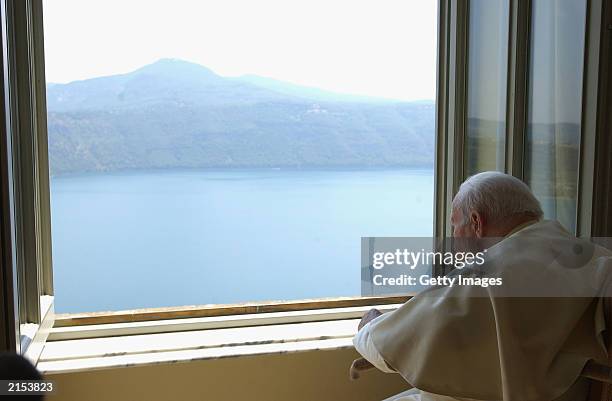 In this handout photo from the Vatican, Pope John Paul II looks over the lake of Albano from a window of his residence in Castel Gandolfo after...