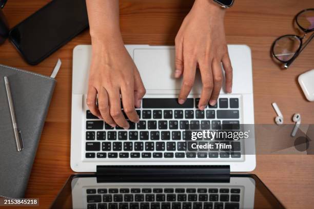 person typing on laptop at wooden desk - journalism stock pictures, royalty-free photos & images
