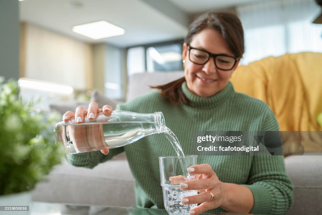 Retrato de una mujer llenando un vaso con agua potable