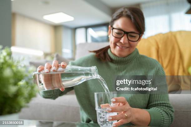 ritratto di una donna che riempie il bicchiere con acqua potabile - ricaricare foto e immagini stock