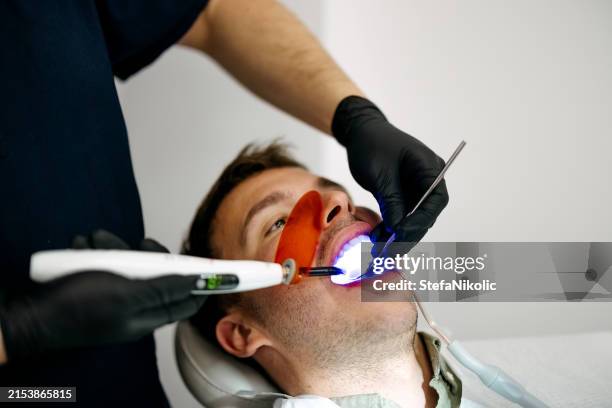 man have a visit in the dentist clinic. - vulling tandartsapparatuur stockfoto's en -beelden