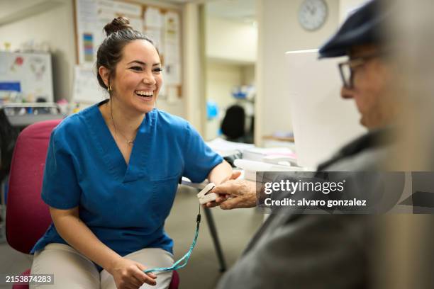 nurse taking blood pressure to elder man - suivi des malades photos et images de collection