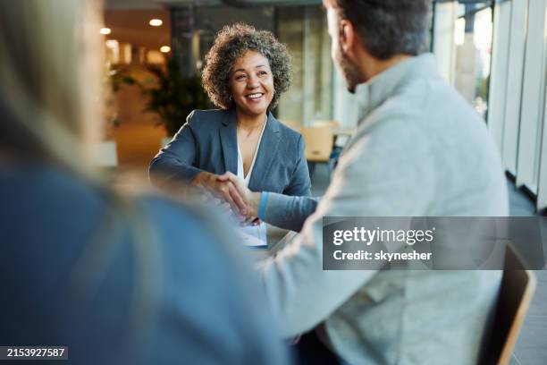 happy insurance agent shaking hands with her customers in the office. - cliente imagens e fotografias de stock