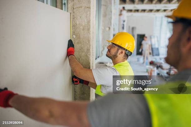 measuring and transporting drywall on a construction site - builders hands stock pictures, royalty-free photos & images