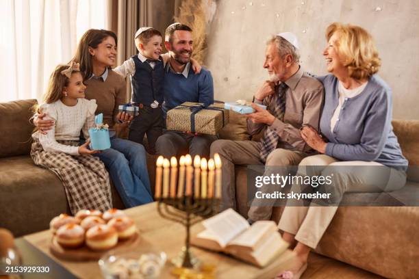 happy extended family exchanging gifts on hanukkah at home. - hanukkah stock pictures, royalty-free photos & images