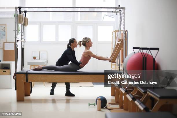 a teacher giving pilates lesson to a woman on a cadillac machine in a studio in paris. - pilates cadillac photos et images de collection