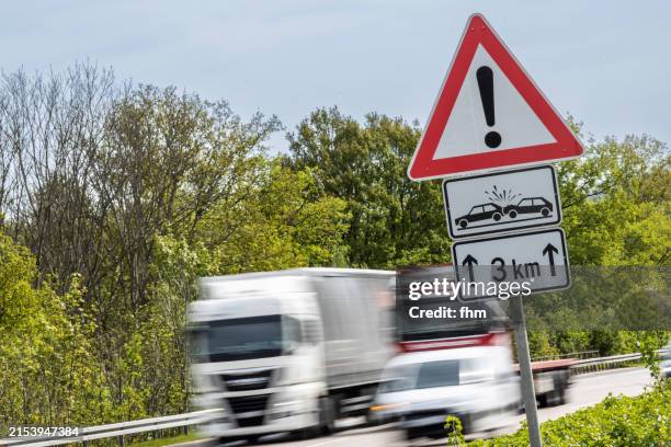 trucks and cars on german autobahn with accident warning sign - autobahn stock pictures, royalty-free photos & images