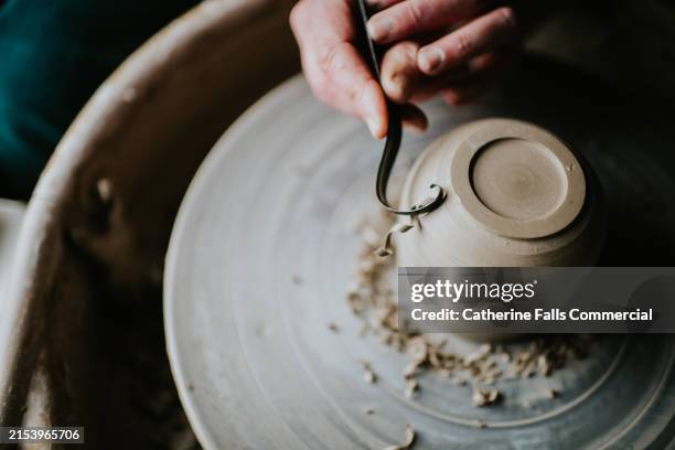 close-up of a woman carefully shaving a clay pot on a potters wheel - accuracy stock pictures, royalty-free photos & images