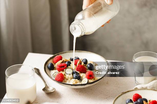 gros plan d’une femme préparant un petit-déjeuner sain avec du lait d’avoine - céréale photos et images de collection