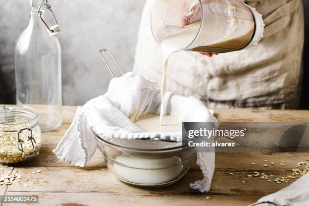 nahaufnahme einer frau, die zu hause hafermilch herstellt - hafermilch stock-fotos und bilder