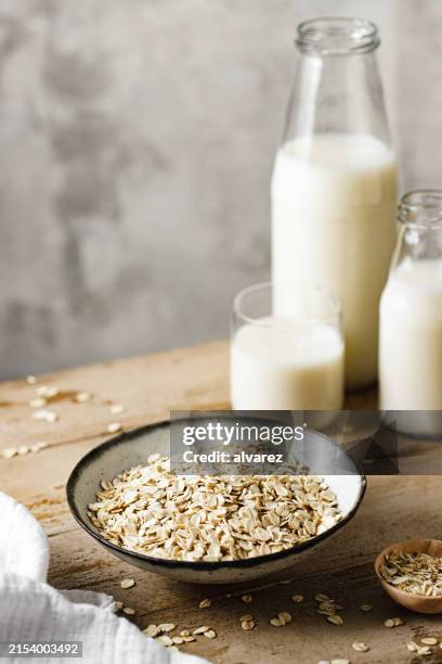 haferflocken in einer schüssel mit hafermilchflaschen auf dem tisch - hafermilch stock-fotos und bilder