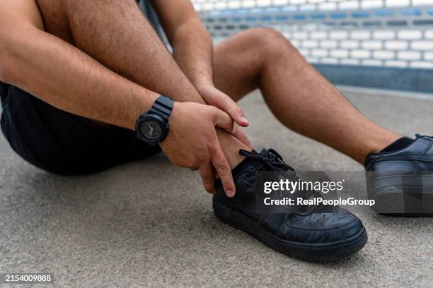man holding leg in pain on bridge - sprain stock pictures, royalty-free photos & images