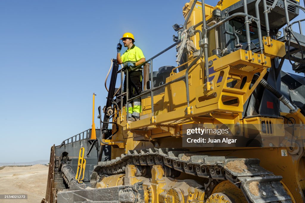 Bulldozer Operator Overlooking Desert Construction Site on a Sunny Day