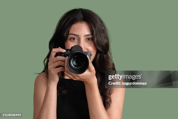 portrait de jeune femme joyeuse prenant une photo avec un appareil photo reflex numérique isolé sur fond vert - photographe photos et images de collection