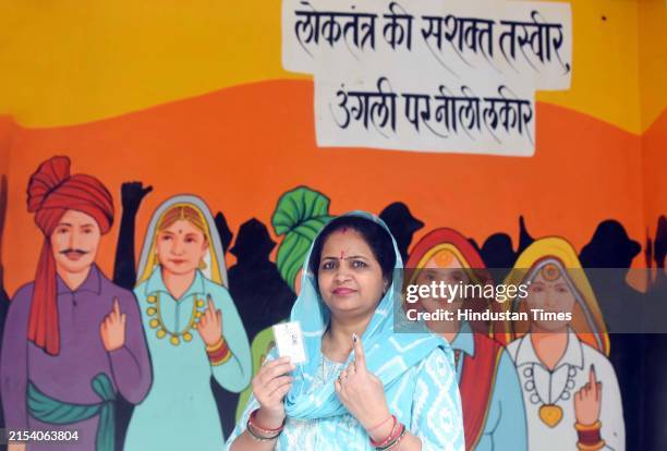 Woman poses for a picture in front of a mural after cast their vote during the sixth phase of Lok Sabha elections in Rampura village, on May 25, 2024...