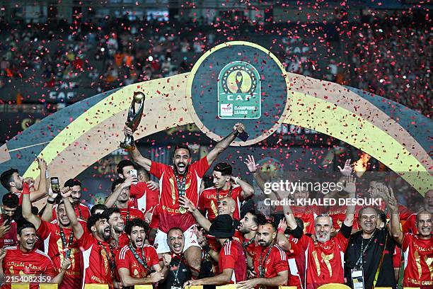 Ahly players celebrate with the winner's trohpy after winning the second leg of the CAF Champions League final football match between Egypt's Al-Ahly...