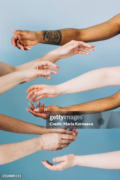 women stretching hands toward each other against blue background. - skin tone stock pictures, royalty-free photos & images