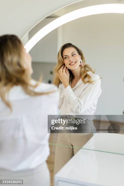 young woman getting ready in front of a mirror - mirror stock pictures, royalty-free photos & images