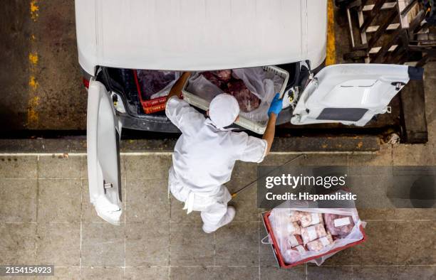 employee loading meat on a van for delivery at a butcher's shop - food truck stockfoto's en -beelden