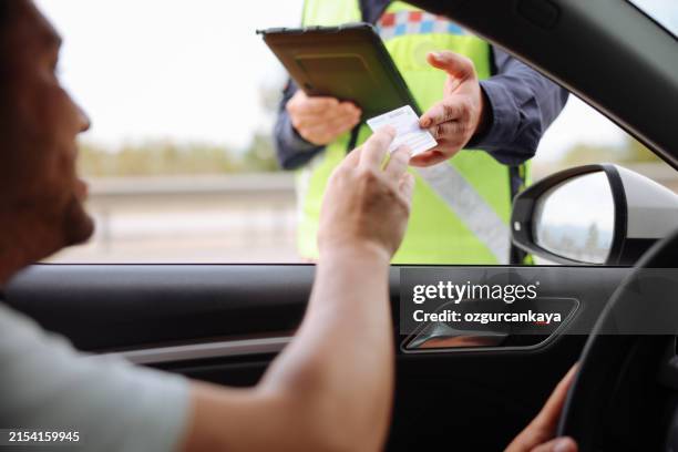 polizist in uniform verkehrskontrolle zu männlichem fahrer - verkehrskontrolle stock-fotos und bilder