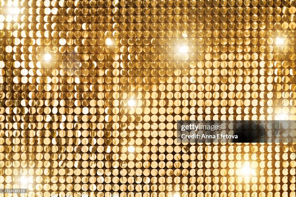 Background from golden sequins in matrix form. Concept of holidays, celebration events and costume parties. Front view