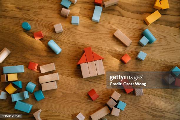 house made of multi-colour building toy blocks on wooden floor - child care stock pictures, royalty-free photos & images