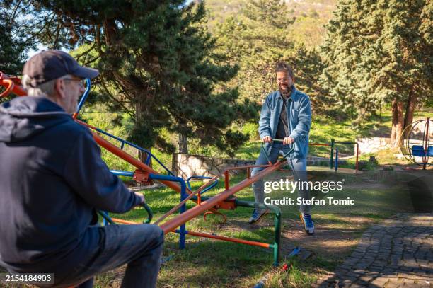 father and son enjoying seesaw at park - gungbräda bildbanksfoton och bilder