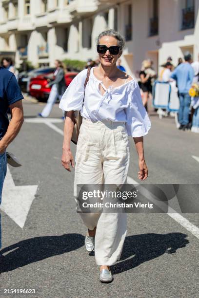Andie MacDowell wears white blouse, high waisted pants during the 77th Cannes Film Festival on May 22, 2024 in Cannes, France.