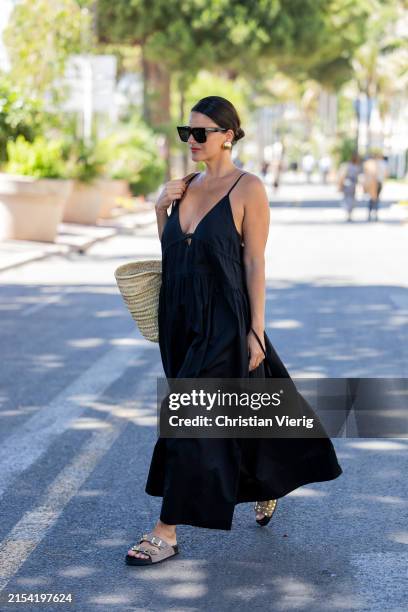 Gili Biegun wears black dress, Celine straw bag during the 77th Cannes Film Festival on May 22, 2024 in Cannes, France.