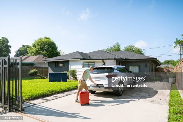 hombre cargando maleta en coche eléctrico - camino de entrada fotografías e imágenes de stock