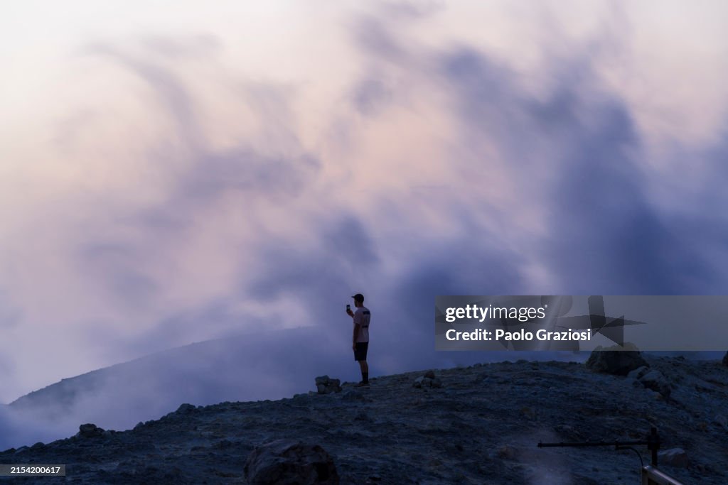 Tourist with smartphone among hot steam of the geothermal area of Vulcano island, Aeolian islands, Italy