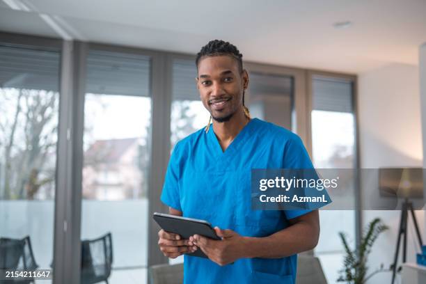 smiling black male nurse holding tablet in modern clinic - male nurse stock pictures, royalty-free photos & images