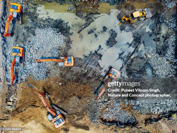a group of mechanical equipment - excavators, vibro hammers, breakers inside a pit excavating / mining the earth - the mh construction stock pictures, royalty-free photos & images