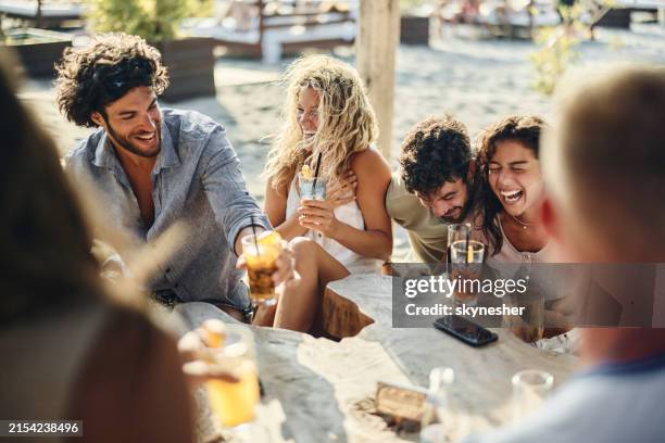 cheerful couples laughing during summer day in a beach café. - beach bar stock pictures, royalty-free photos & images