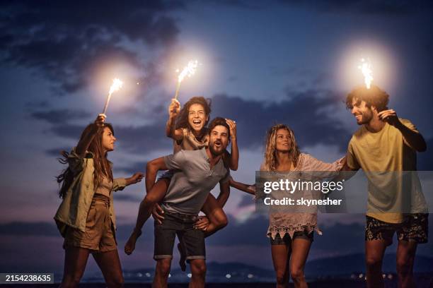 de jeunes amis insouciants s’amusent avec des torches enflammées la nuit. - flambeau photos et images de collection