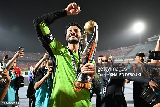 Ahly's Egyptian goalkeeper Mohamed el-Shenawy celebrates with the trophy after the second leg of the CAF Champions League final football match...