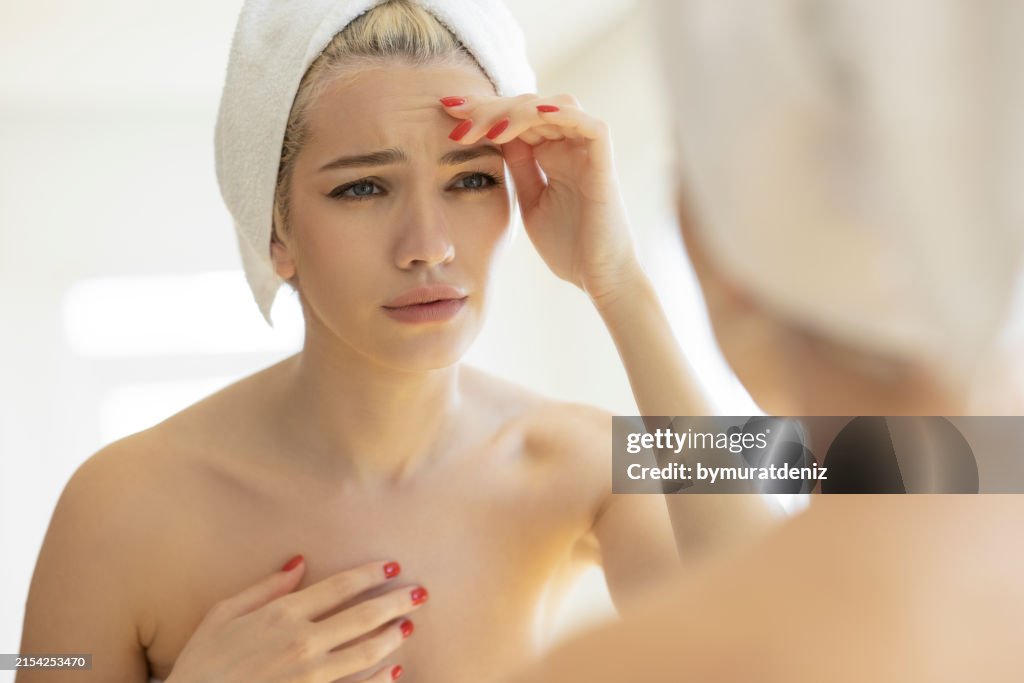 Verärgerte junge Frau, die erste Falten überprüft