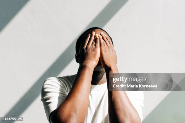 african american man tired and stressed, covered his face with his hands. mental health, prevention of burnout and depression. - hoffnungslosigkeit stock-fotos und bilder