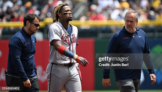 Ronald Acuña Jr. #13 of the Atlanta Braves walks off the field with trainers after an apparent injury in the first inning during the game against the...